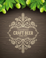 Green hops and flourishes beer emblem on a wooden plank background - vector illustration