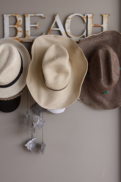 Hat rack with straw beach hats and a silver fish wind chime.