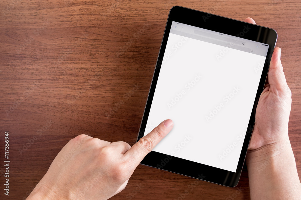 Poster hand touch on empty screen of tablet above brown table top view,