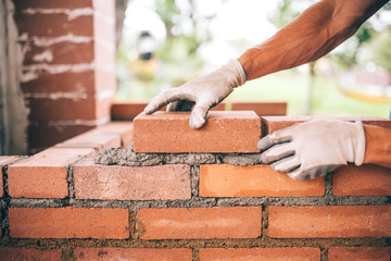 professional construction worker laying bricks and building barbecue in industrial site. Detail of hand adjusting bricks - obrazy, fototapety, plakaty