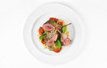 Rack of lamb with bulgur, dried tomatoes and lemon Moroccan on a plate on a white background, top...