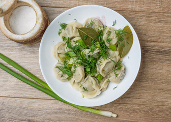plate of traditional Russian dumplings sprinkled with herbs on wooden table