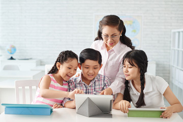 Schoolchildren and teacher working with tablet computer