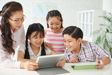 Children and teacher gathered in front of tablet computer
