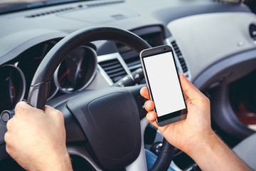 Young man driving a car with a phone in his hand. Multitasking. Don't text and drive