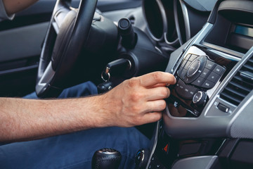 Naklejka premium Car dashboard. Radio closeup. Man sets radio