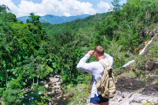 The tourist with a backpack examines vicinities from the mountain.
