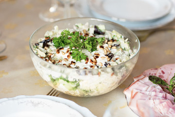 Meat snack for dinner on the dinner table. Salad with duck, mushroom, cucumber and plum with mayonnaise in a glass dish.