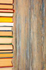 Books on grunge wooden table desk shelf in library. Back to school background, copy space for your ad text. Old hardback book with no labels, blank spine