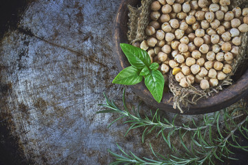 Garbanzo beans (chickpeas) with basil in clay bowl on metallic rustic background. Top view with copy space