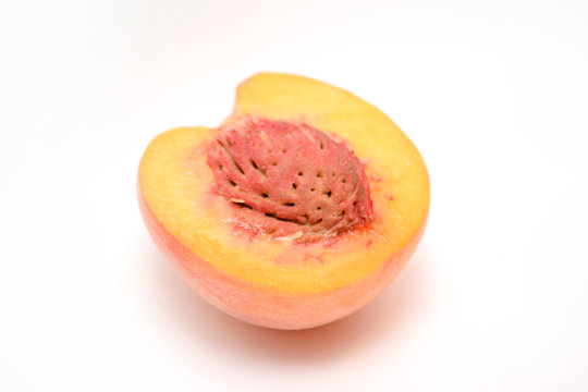 half juicy peach with a stone on a white background