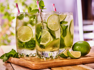 Alcohol drink. On wooden boards small group glasses with alcohol drink and ice cubes. A drink number three hundred one cocktail mohito with knife and mint leaf. Country life. Light background.