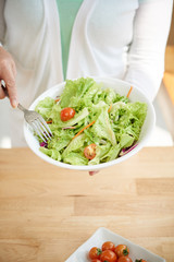Woman holding a big bowl of fresh salad she made