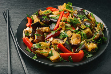 Appetizer - asian salad with eggplants, paprika and garlic on black background.