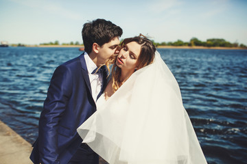 Groom leans to bride's face while she enjoys a wind with closed