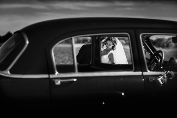 Obraz na płótnie Canvas A view on the kissing newlyweds through the old cars windows