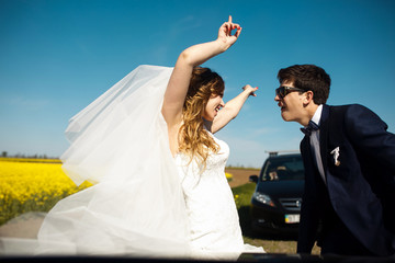 Bride and groom dance standing on the road in a sunny day