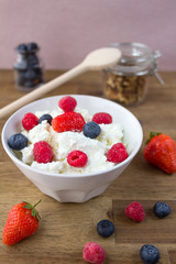 cottage cheese with berries and nuts on wooden table. healthy breakfast