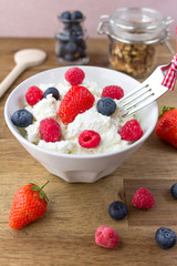 cottage cheese with berries and nuts on wooden table. healthy breakfast