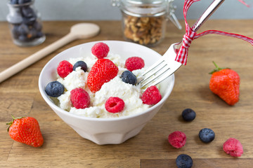 cottage cheese with berries and nuts on wooden table. healthy breakfast