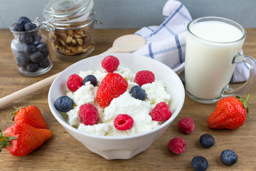 cottage cheese with berries, milk and nuts on wooden table. healthy breakfast