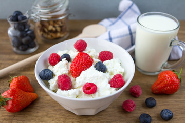 cottage cheese with berries, milk and nuts on wooden table. healthy breakfast