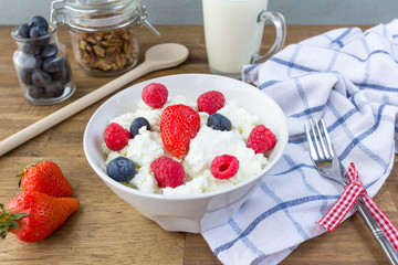 cottage cheese with berries, milk and nuts on wooden table. healthy breakfast