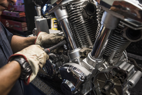 Close-up of mechanic fixing motorbike motor