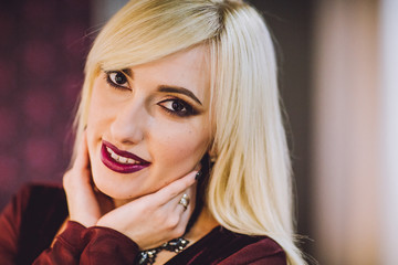 Beautiful fashion blond woman posing near the mirror and gets makeup. Young beautiful model smiling...