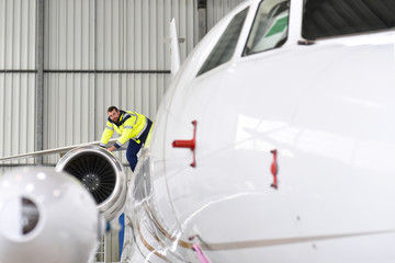 Mechaniker kontrolliert Triebwerk eines Flugzeuges im Hangar // Mechanic controlled engine of an...