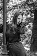 Young beautiful teenager girl with long hair walking in Striysky park in Lviv, posing near a lamp to illuminate the bushes and trees