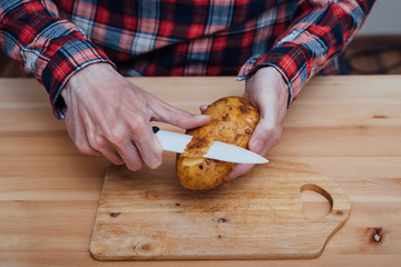 Man hands slicing fresh potato by ceramic knife