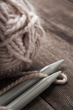 yarn with knitting needles on a wooden background.