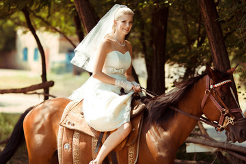 Obraz na płótnie Canvas Funny bride in the bridal dress rides a horse