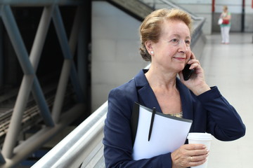 Business woman in the airport or train subway metro station making a phone call with smartphone