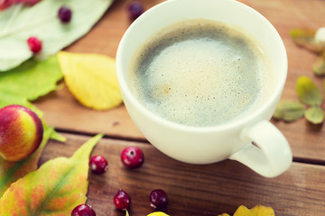 close up of coffee cup on table with autumn leaves