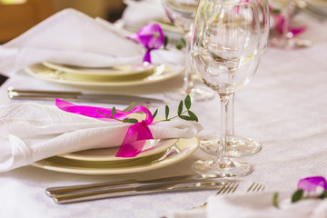 Wedding summer table decoration with flowers. White plates, forks, knifes and wineglasses