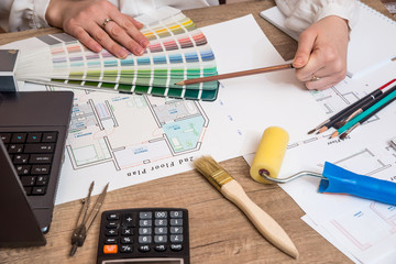 Architect sketching a construction project with laptop, color palette and work tools
