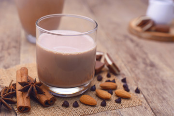 Glass of chocolate milk on wooden table.