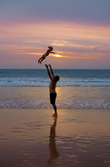 Fototapeta na wymiar Father throws his daugter at the beach near the sea at the spect