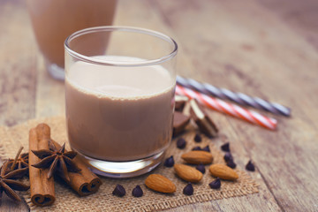 Glass of chocolate milk on wooden table.