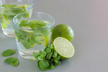 Mojito cocktail with lime and mint in glass on a grey background