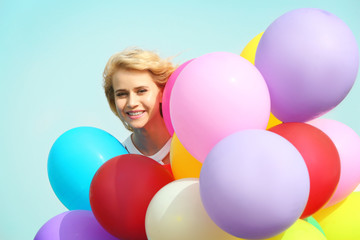 Fototapeta na wymiar Happy woman with colorful balloons on blue sky background