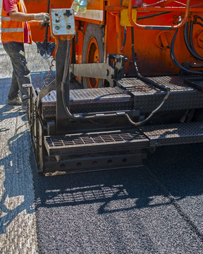 close-up details of industrial machinery working with asphalt, mixing bitumen with hot asphalt, layering on the road surface