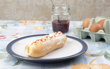 Image of a cream cake and strawberry jam and eggs on a table 