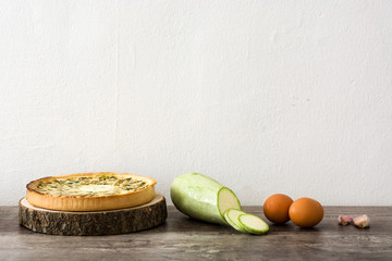 French quiche Lorraine with vegetables on a rustic wooden table

