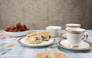 Image  of scones with jam, tea and strawberries on a table 