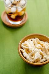 close up in dried squid and cola in glass on green background