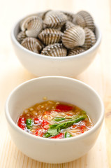 steamed blanched clams in white bowl and spicy dipping sauce on