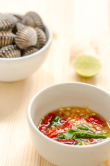 steamed blanched clams in white bowl and spicy dipping sauce on